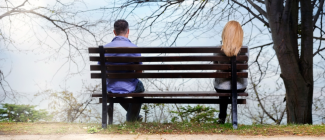 Couple sitting separated on park bench_0